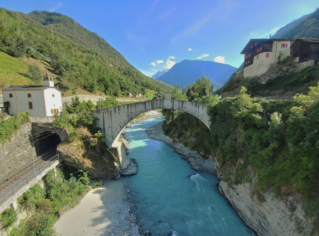 historic stone arch bridge over a turquoise river in the Mattertal Valley near Zermatt, Switzerland