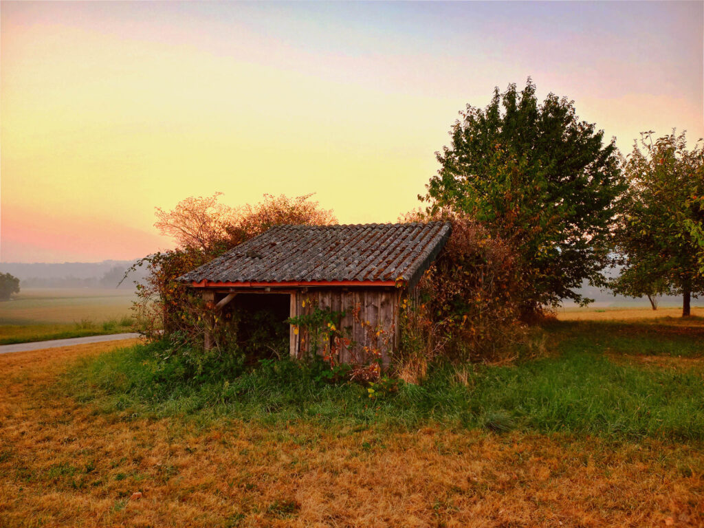 Early morning sunrise over a small wooden farm shed in the countryside of Fribourg canton, Switzerland