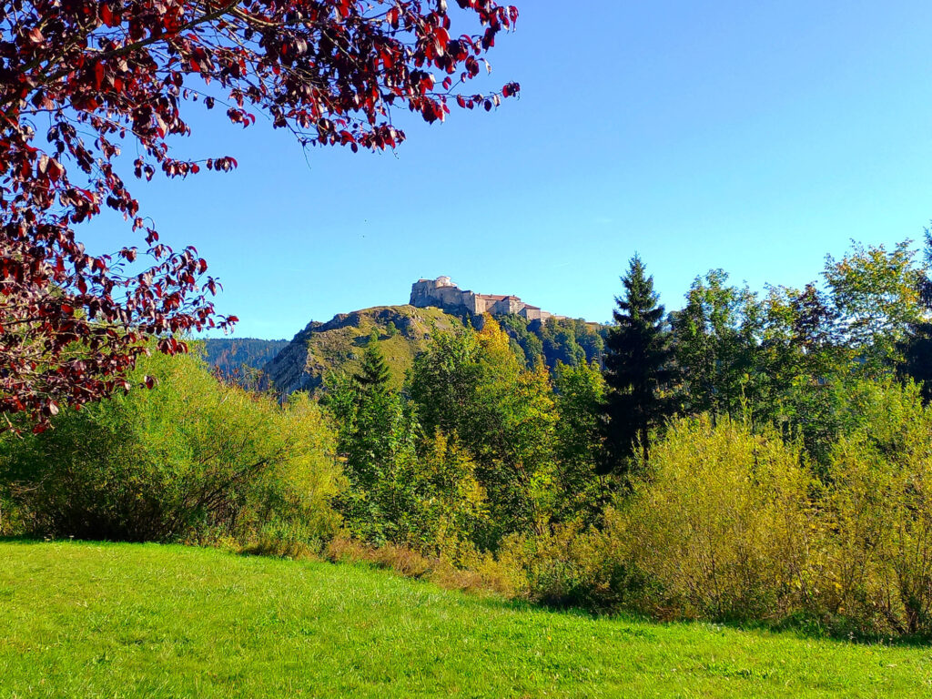 distant view of Château de Joux rising above forested hills in the Doubs region France