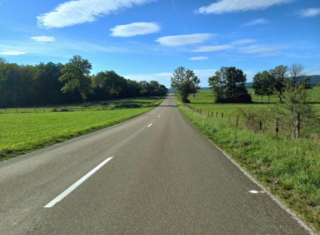 quiet country road through green fields in the Jura region of eastern France, photographed during a bicycle ride