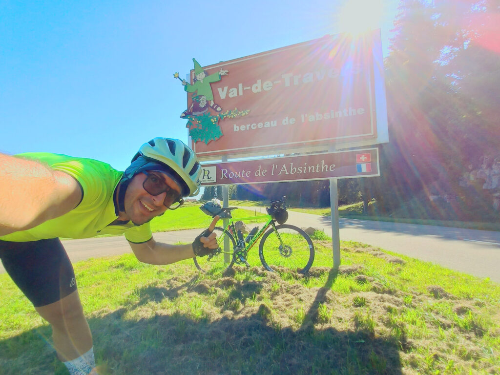 cycling selfie beside a Route de de l’Absinthe sign near the Swiss-French border in Val-de-Travers