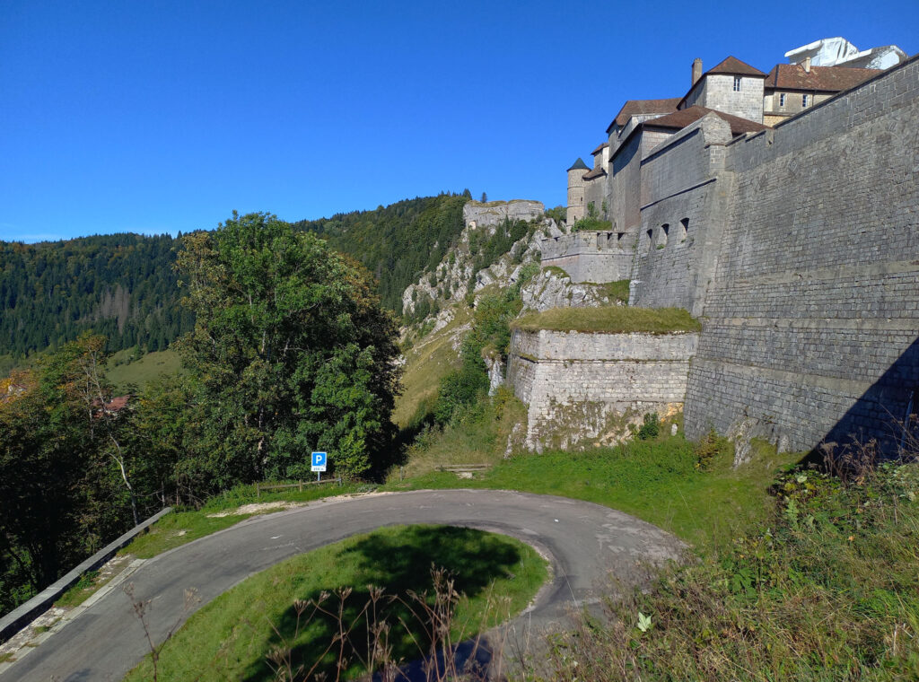 serpentine access road below Château de Joux with fortress walls rising above in the Doubs region of France