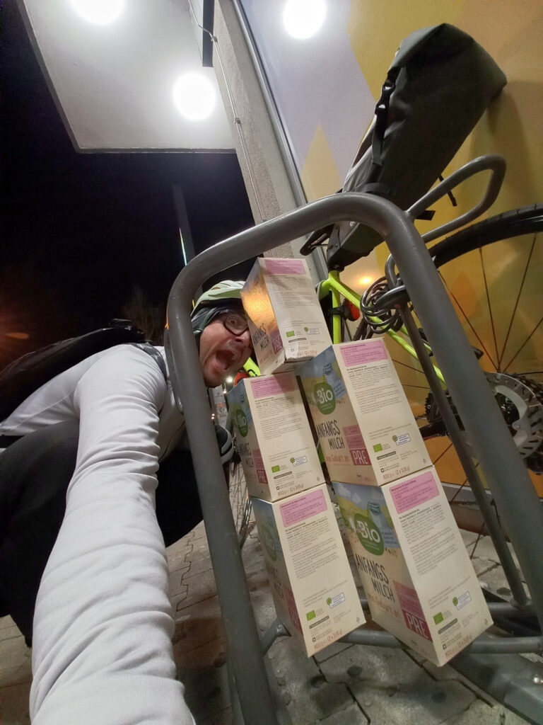 Cycling selfie during an evening stop in Germany with stacked baby formula boxes beside the bike