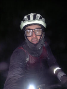 Cyclist covered in frost during a freezing winter night ride, with icy glasses, helmet, balaclava and frozen clothing