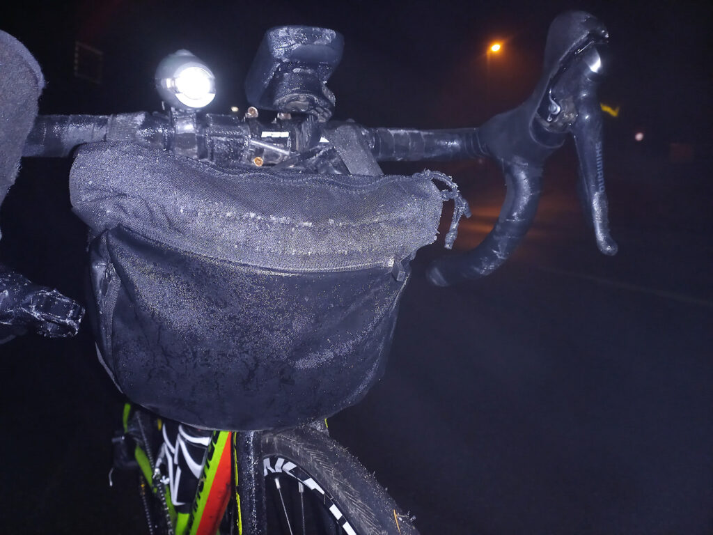 Frozen cycling cockpit and front handlebar bag covered in ice and moisture during a cold winter night ride