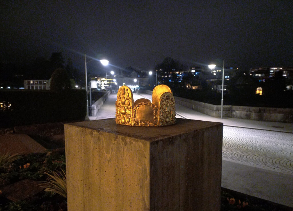 Golden crown sculpture illuminated during a cold night near the Swiss-German border