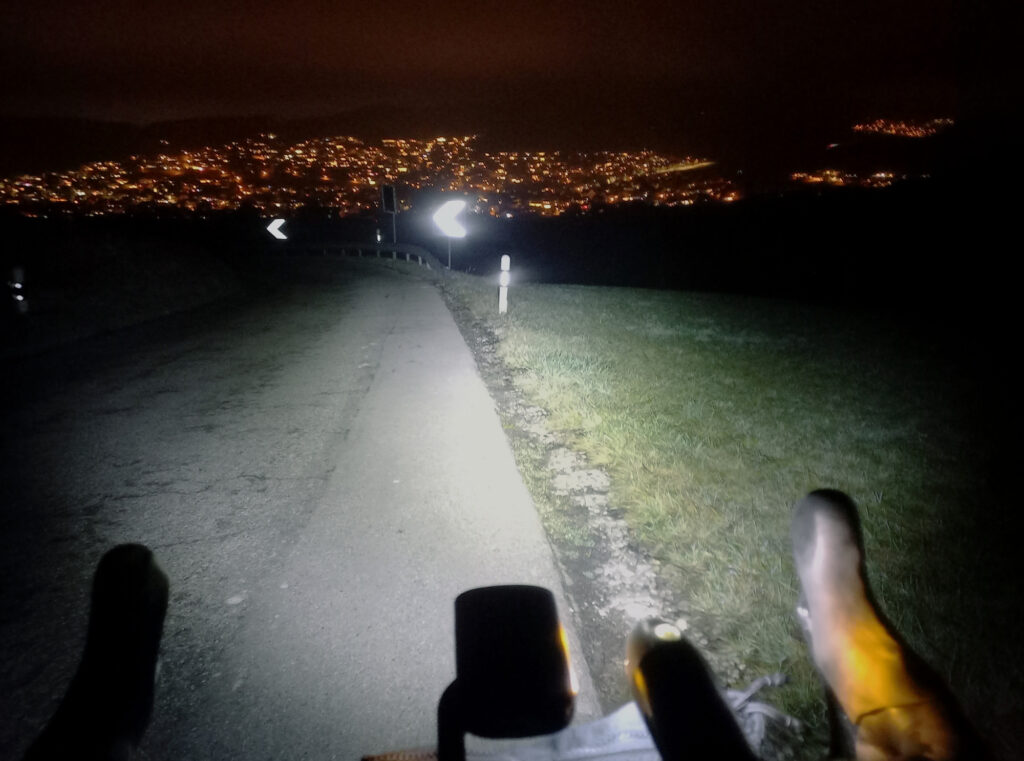 Night cycling view over glowing Swiss town lights during a cold winter night