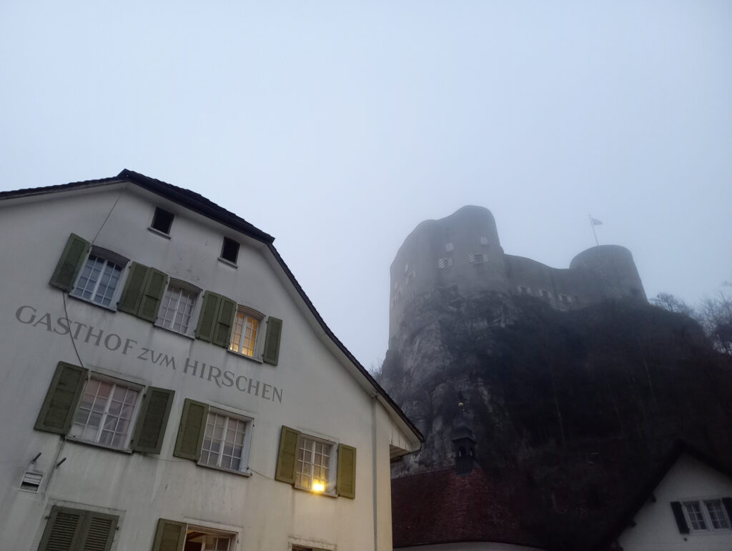 Old Falkenstein Castle rising above a foggy Swiss village during a cold winter cycling ride
