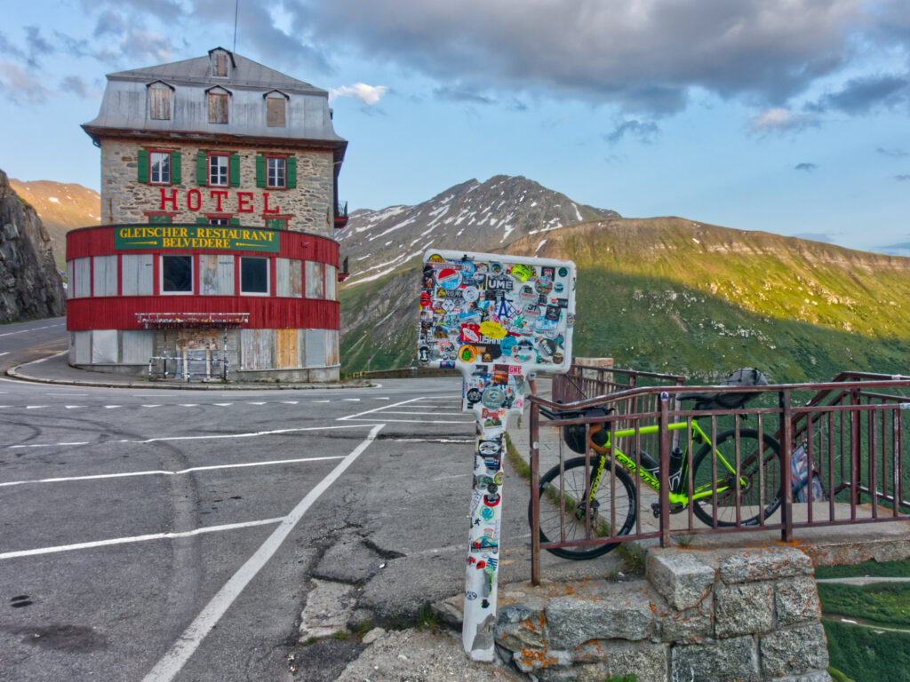 Hotel Belvédère with a sticker-covered road sign and bicycle on Furka Pass.