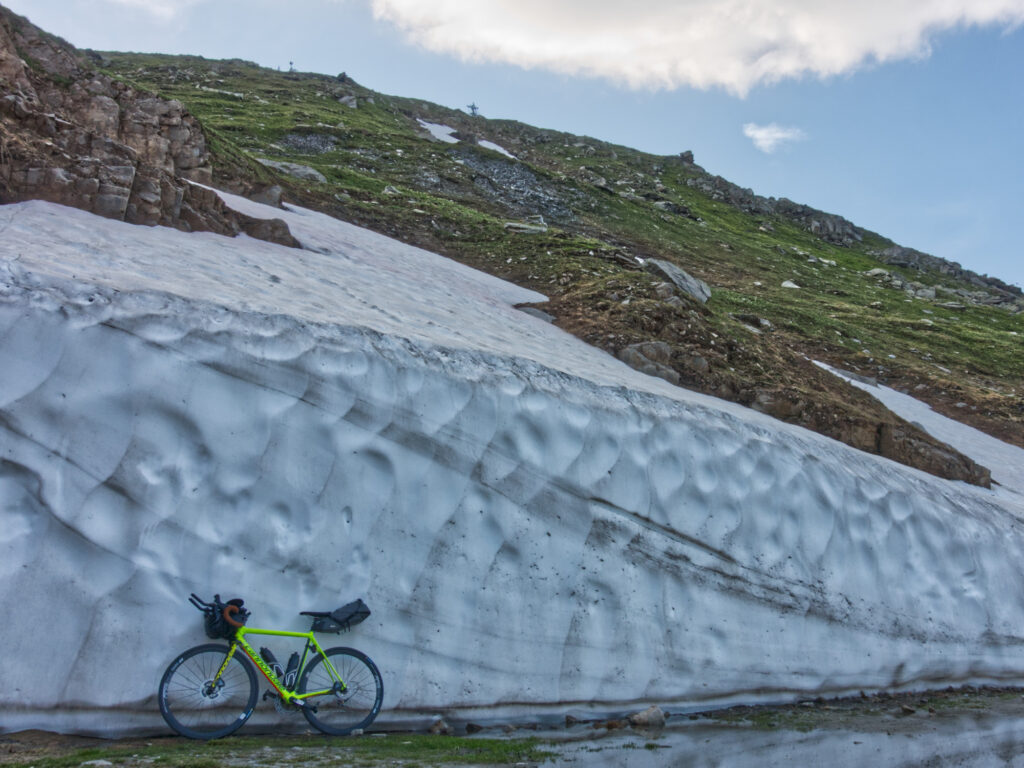 Road bike beside a snowbank at the summit of Furka Pass.